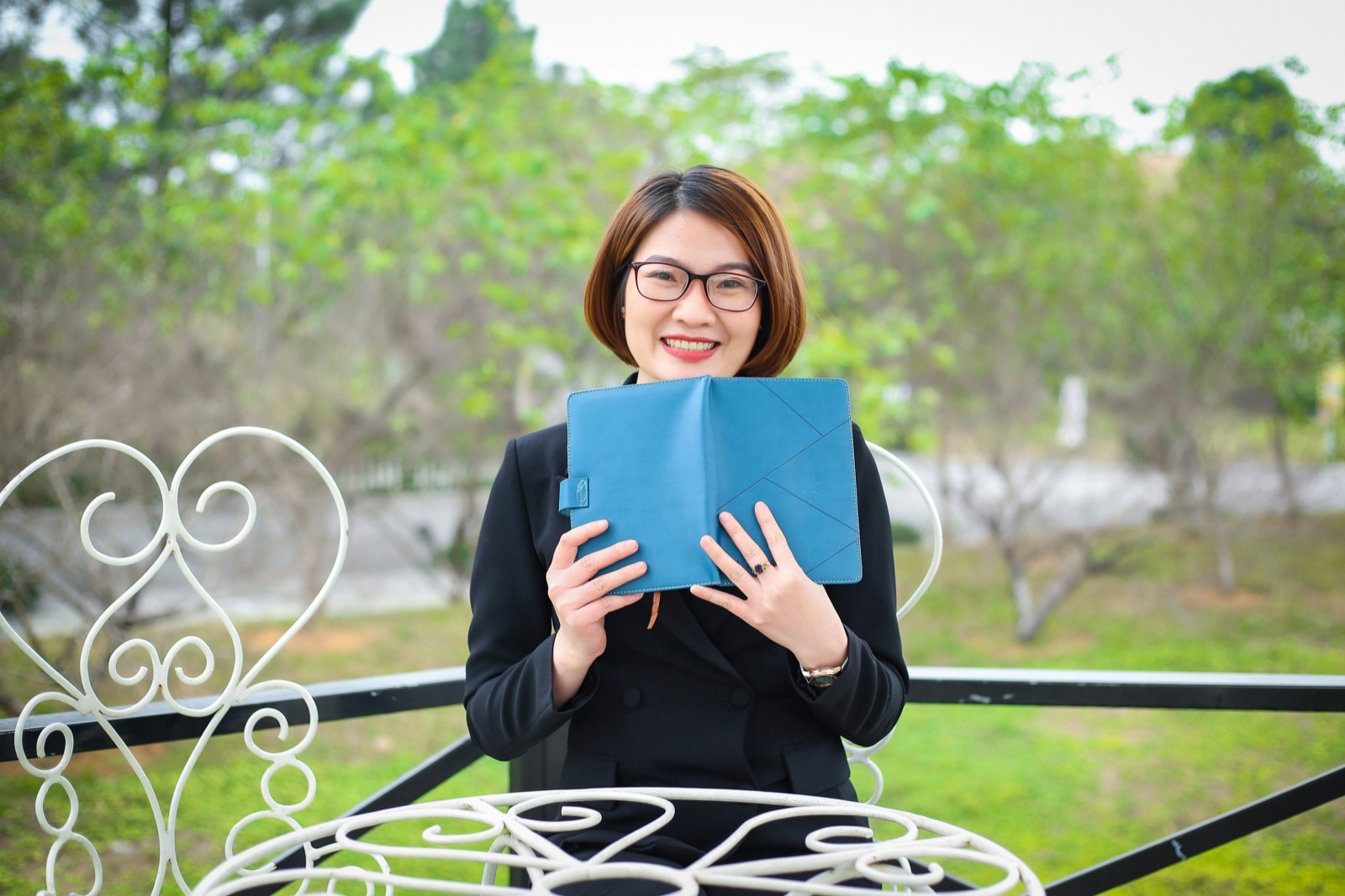 A smiling Mandarin teacher holding a lesson notebook
